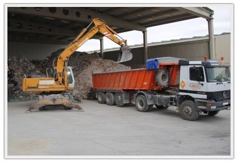 Una excavadora amarilla está cargando un camión volquete rojo