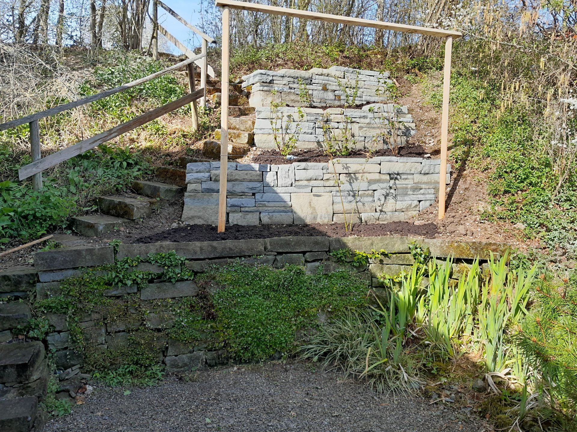 Steinstufen mit Holzgeländern auf einem sonnenbeschienenen Hangweg