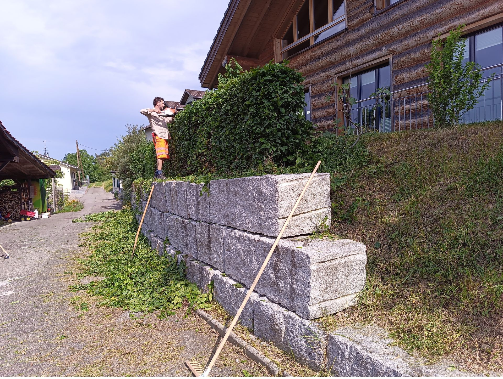 Ein mit Weinreben bewachsenes Spalier neben einem Haus mit Blick auf einen grünen Hangweg