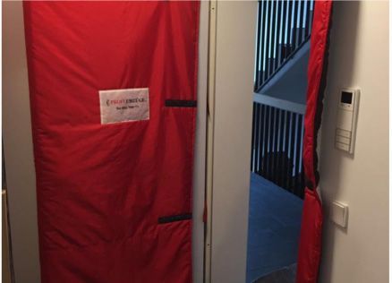 Eine rote Abdeckung bedeckt eine Tür in einem Raum mit einer Treppe im Hintergrund.