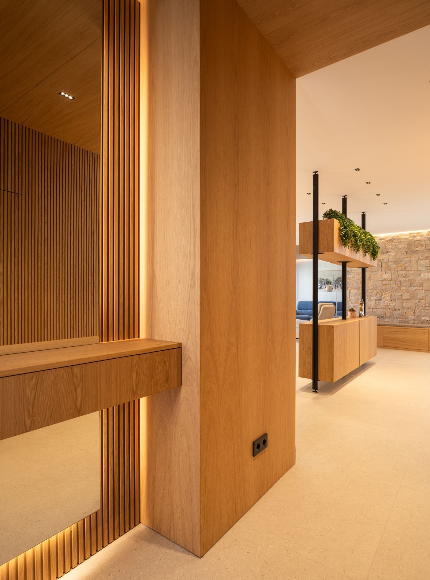 Un interior moderno con paredes revestidas de madera, iluminación lineal, una estantería flotante