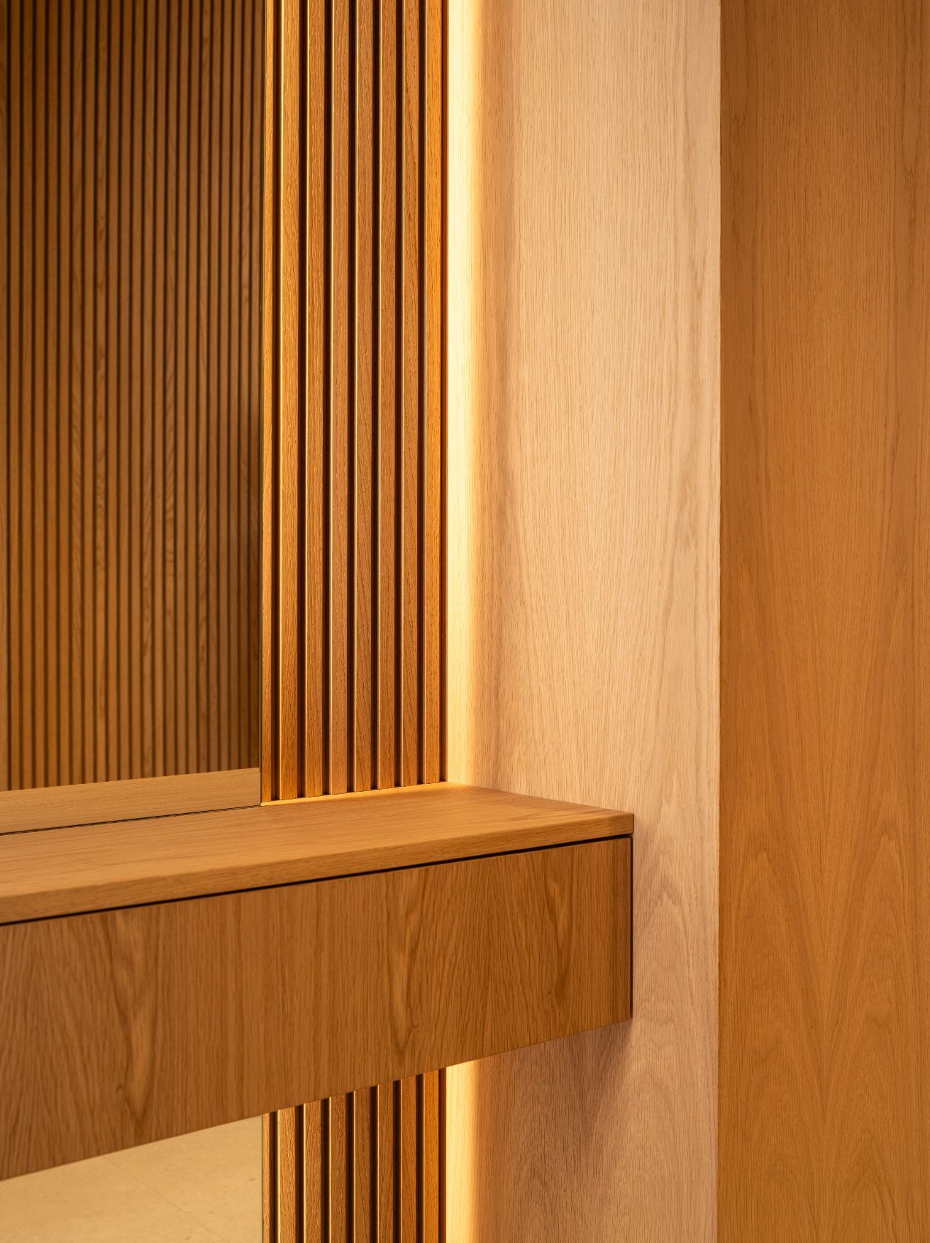 Primer plano de un interior moderno con una estantería de madera flotante sobre un fondo de listones