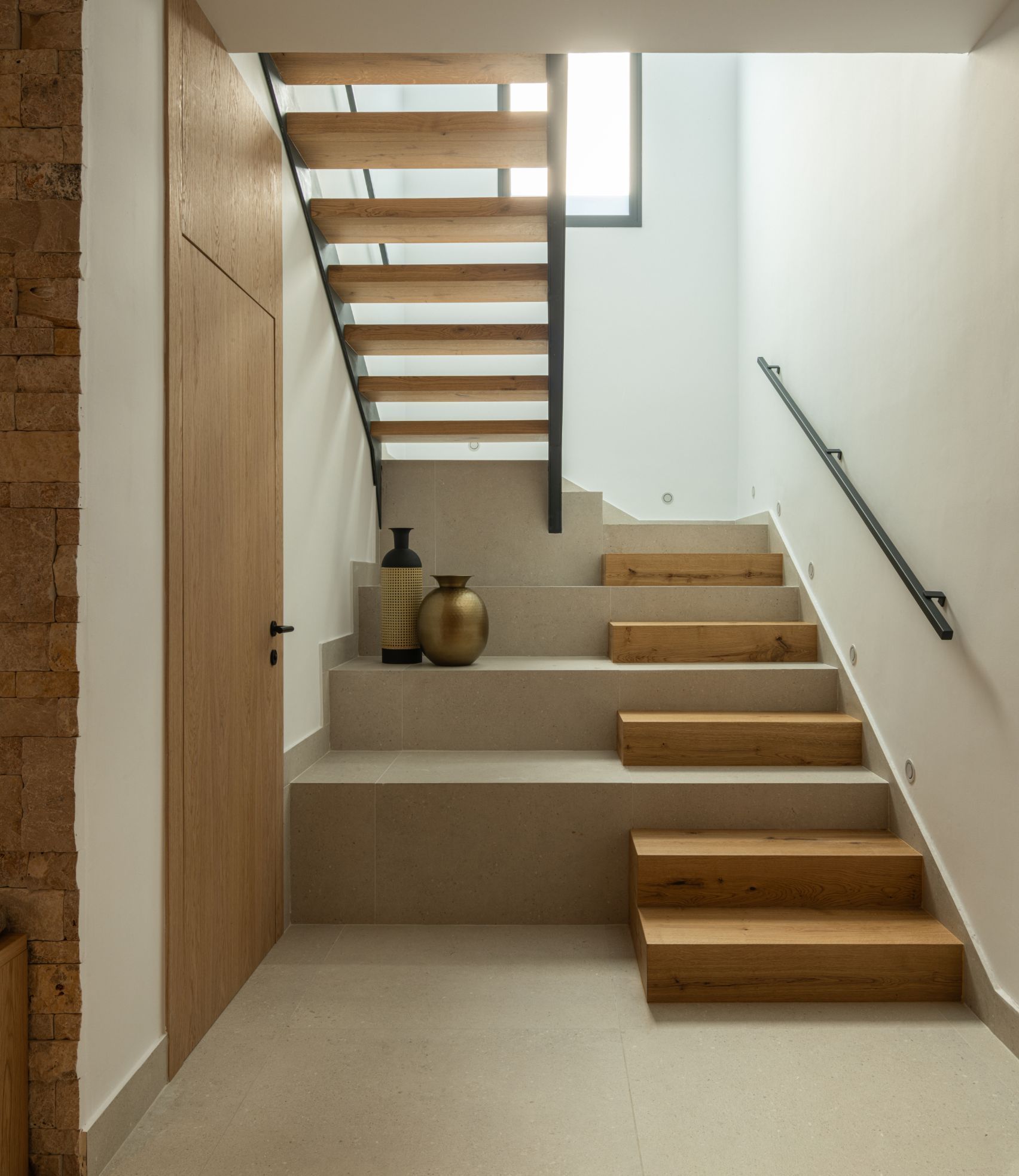 Una escalera moderna con peldaños de madera y escalones de hormigón claro, adornada con jarrones decorativos 