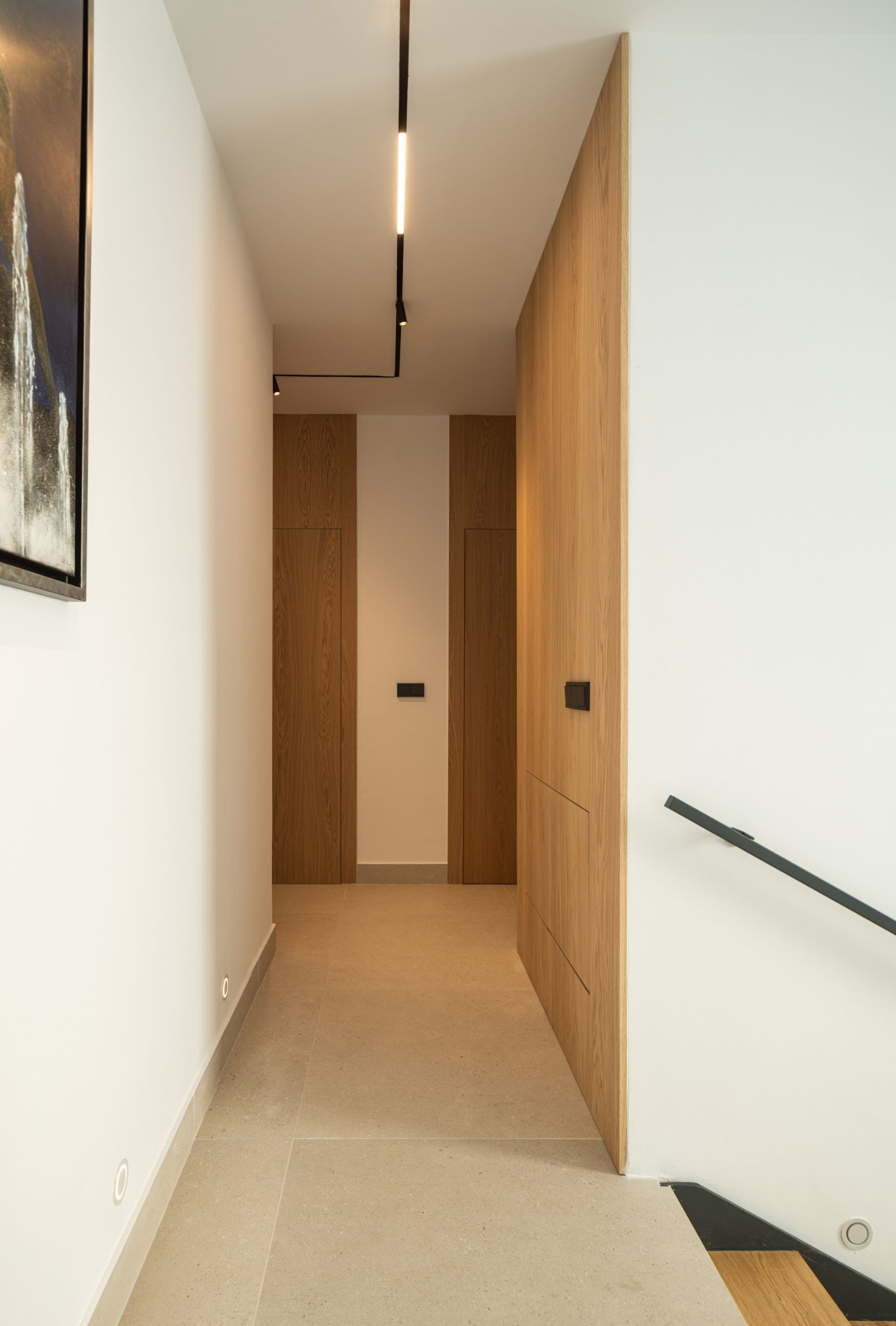 Un pasillo luminoso y moderno con paneles de madera, paredes blancas, iluminación minimalista