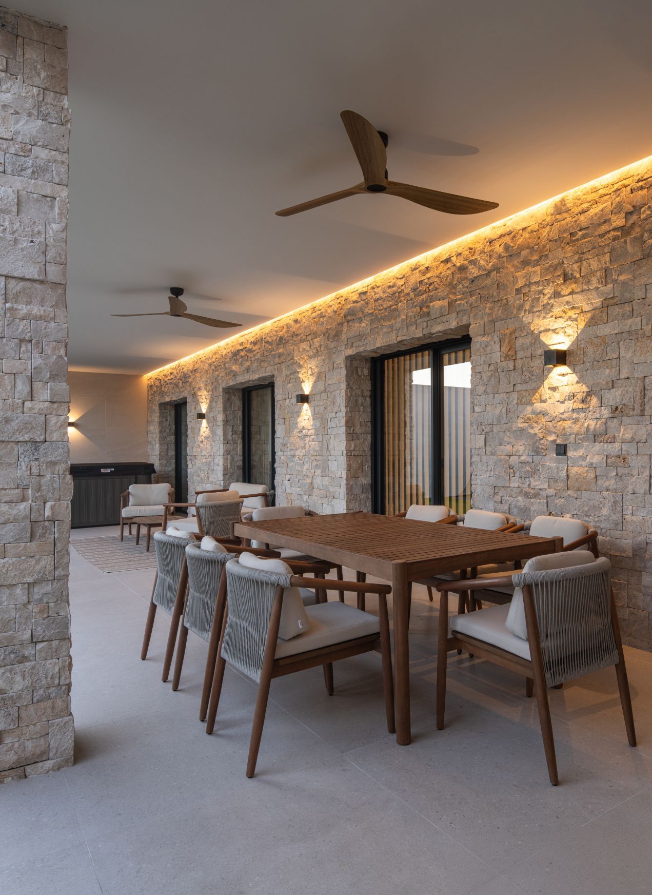 Una mesa de comedor de madera con seis sillas en un patio cubierto con una pared de piedra