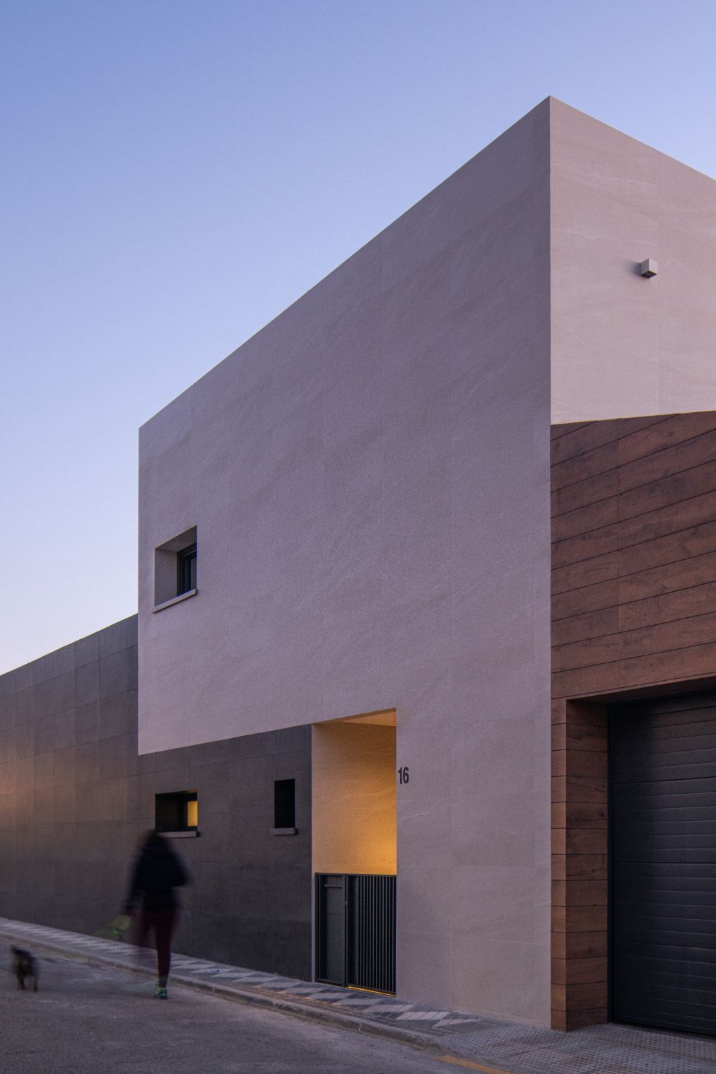 Edificio moderno con paredes texturizadas en tonos gris claro, gris oscuro y revestidas de madera.