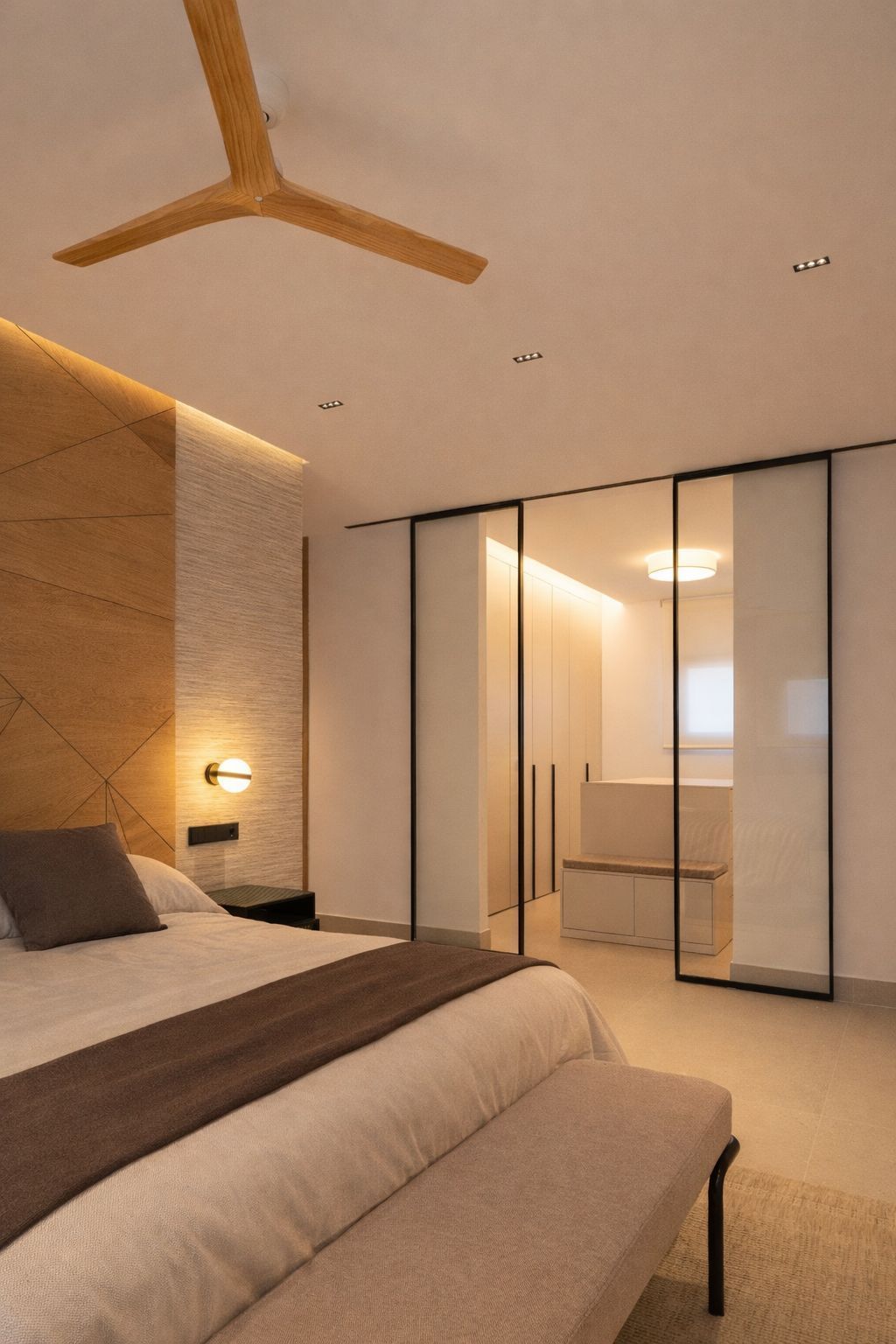 Un dormitorio moderno con una pared decorativa de madera, una cama de color neutro y puertas correderas de cristal 