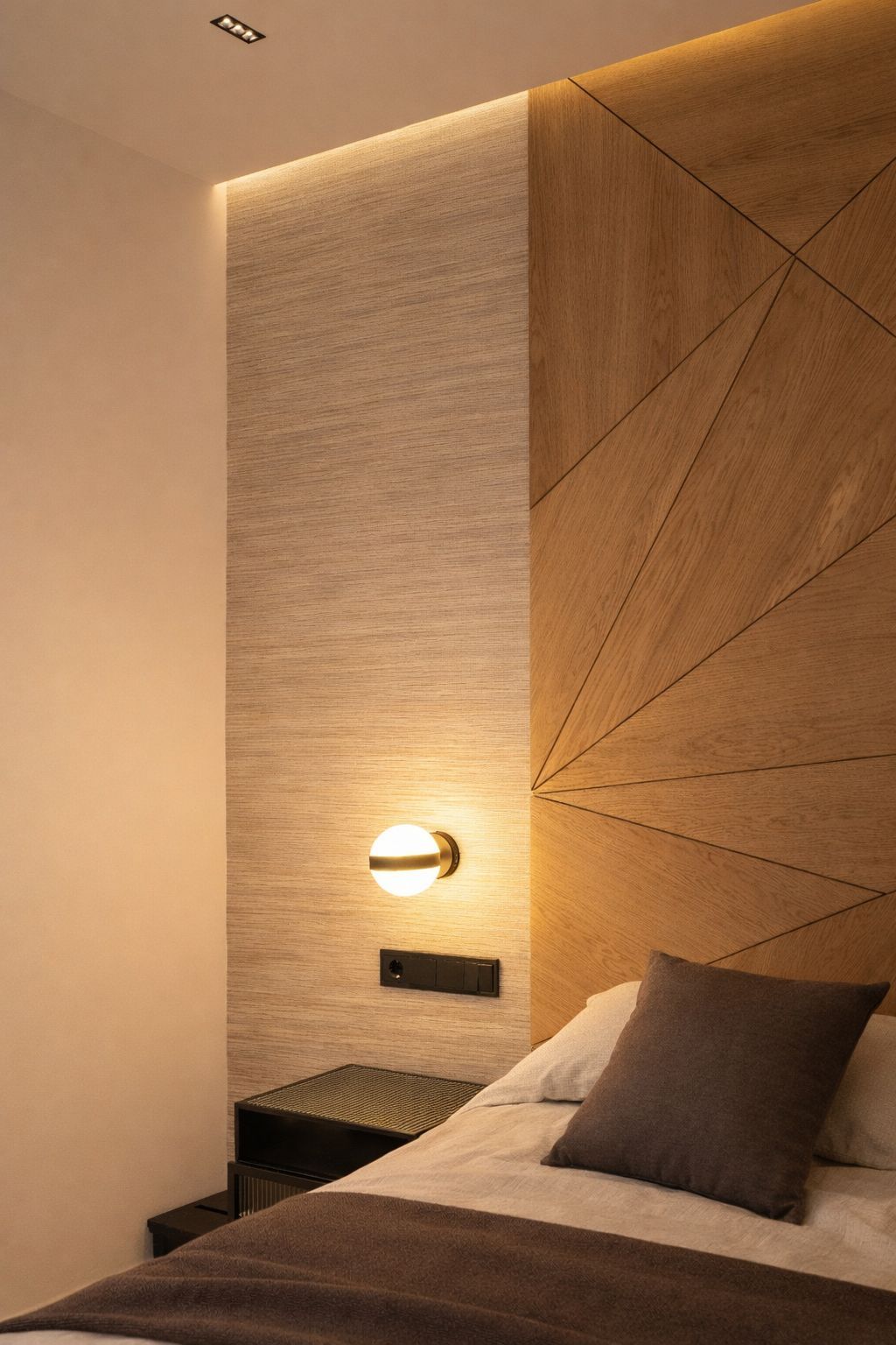 Un dormitorio con una pared de color beige texturizado, cabecero revestido de madera con líneas geométricas