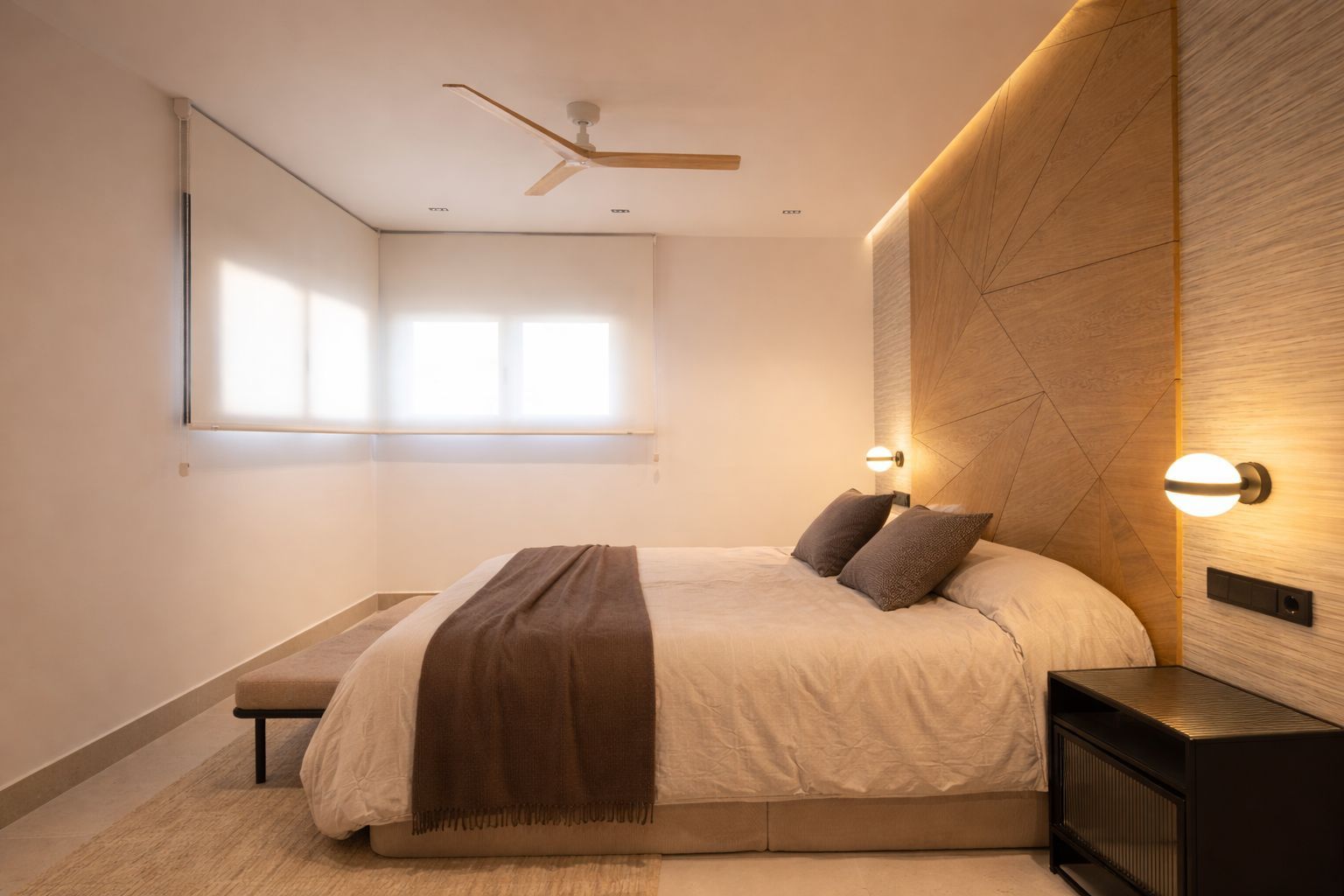 Un dormitorio moderno en tonos neutros con cabecero de madera, iluminación ambiental suave