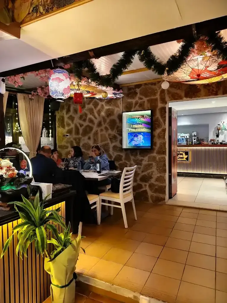 Interior de un restaurante. Personas sentadas a una mesa, pared de piedra, decoración asiática.