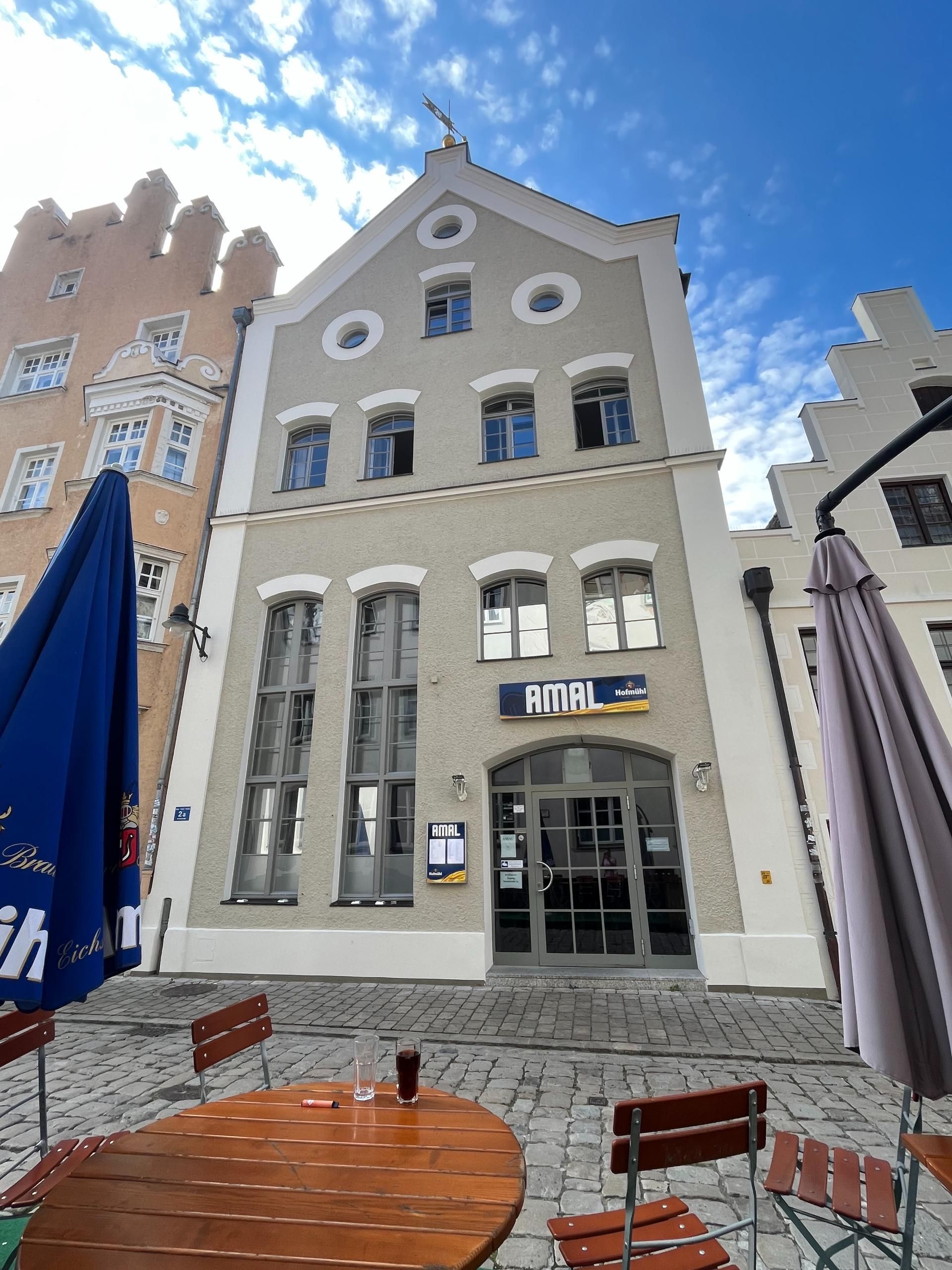 Fassade eines historischen Gebäudes in hellgrau mit großen Fenstern – Außenanstrich durch die Malerei Segerer Werkstätte.