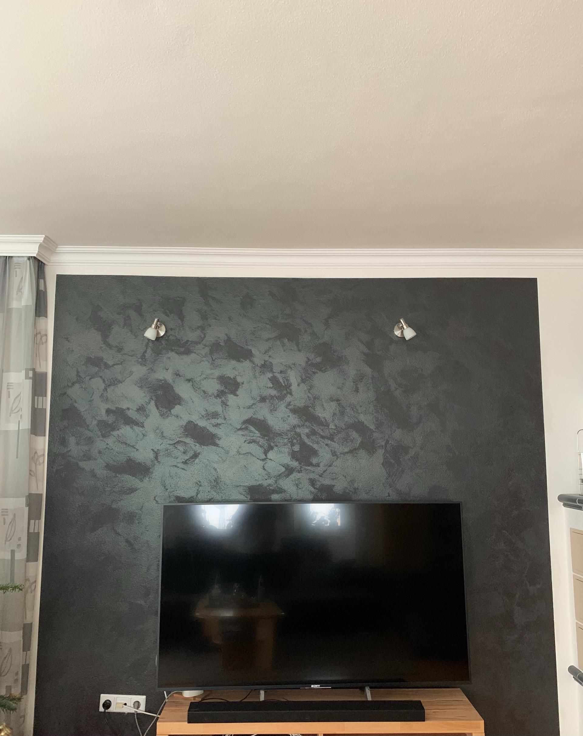 Dunkelgraue Akzentwand mit Strukturputz hinter Fernseher – moderne Wandgestaltung durch die Malerei Segerer.