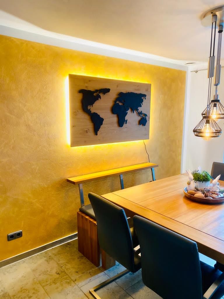 Esszimmer mit goldgelber Wandfarbe und beleuchtetem Weltkarten-Wandbild – kreative Innenraumgestaltung der Malerei Segerer.