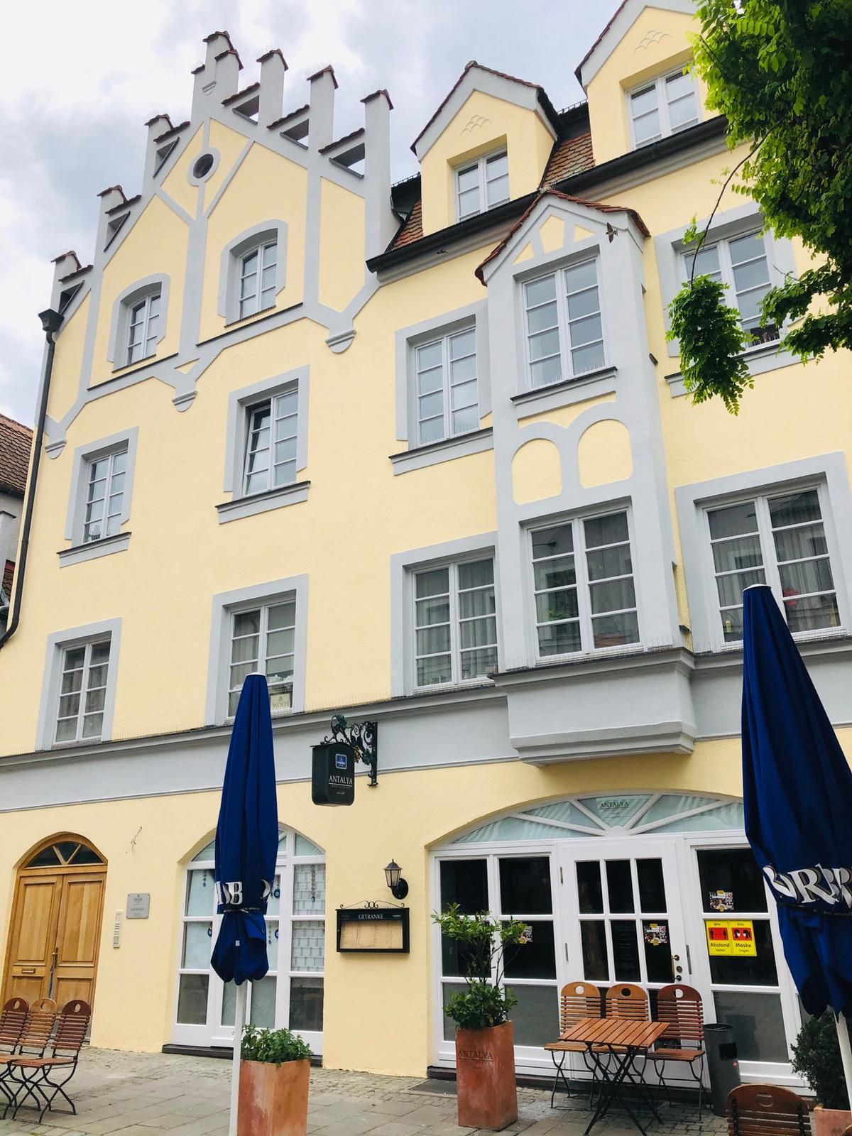 Gelb gestrichenes Altstadthaus mit hellen Fensterrahmen – Fassadengestaltung von der Malerei Werkstätte.