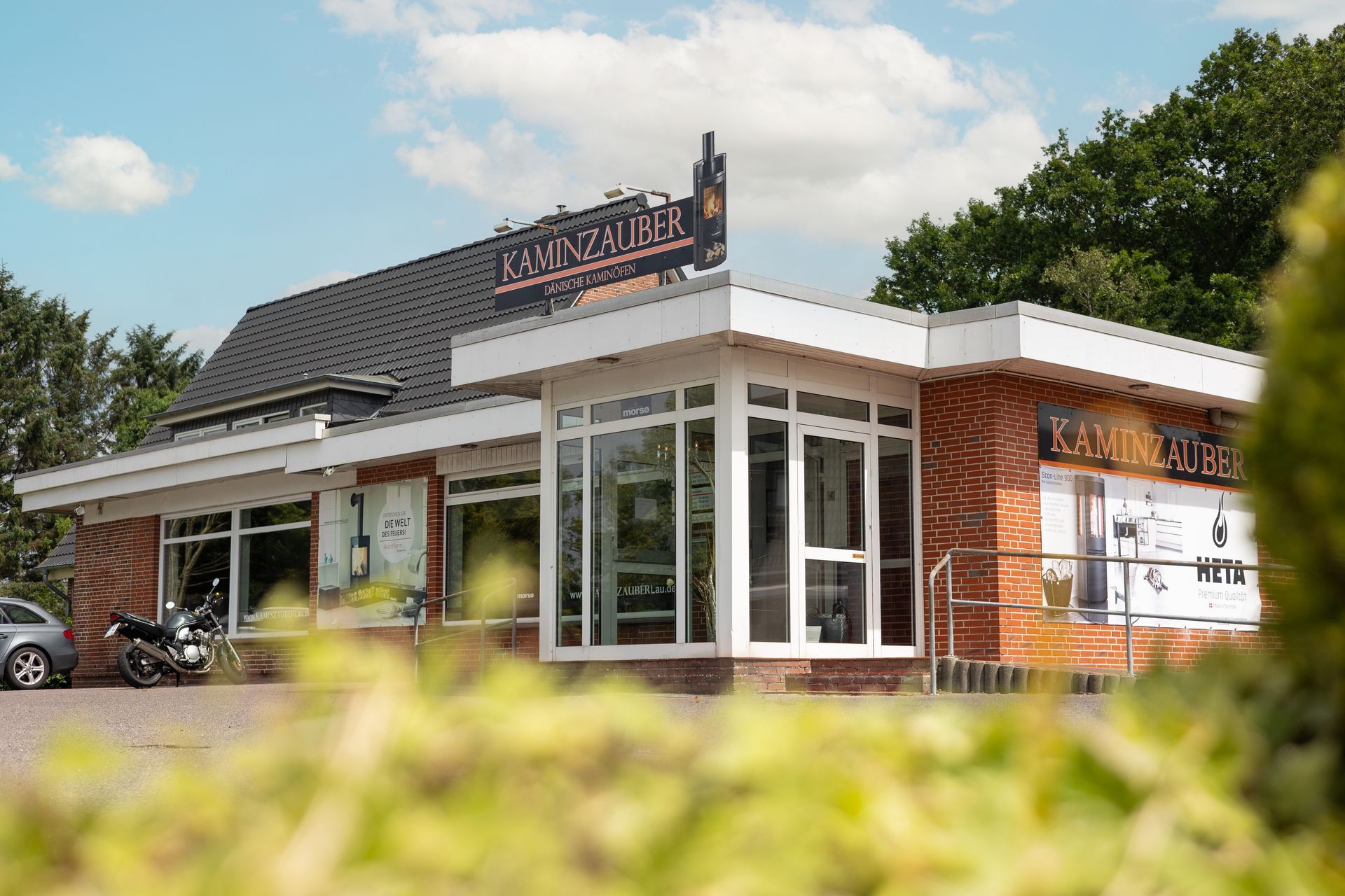 Ein weißer Anhänger steht vor einem Gebäude mit der Aufschrift Kaminzauber