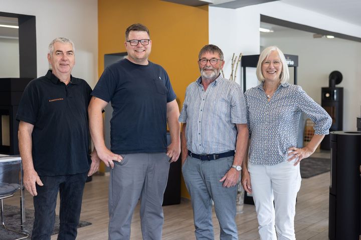 Eine Gruppe von Menschen sitzt an einem Tisch in einem Wohnzimmer.
