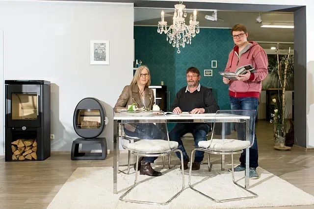 Eine Gruppe von Menschen sitzt an einem Tisch in einem Wohnzimmer.