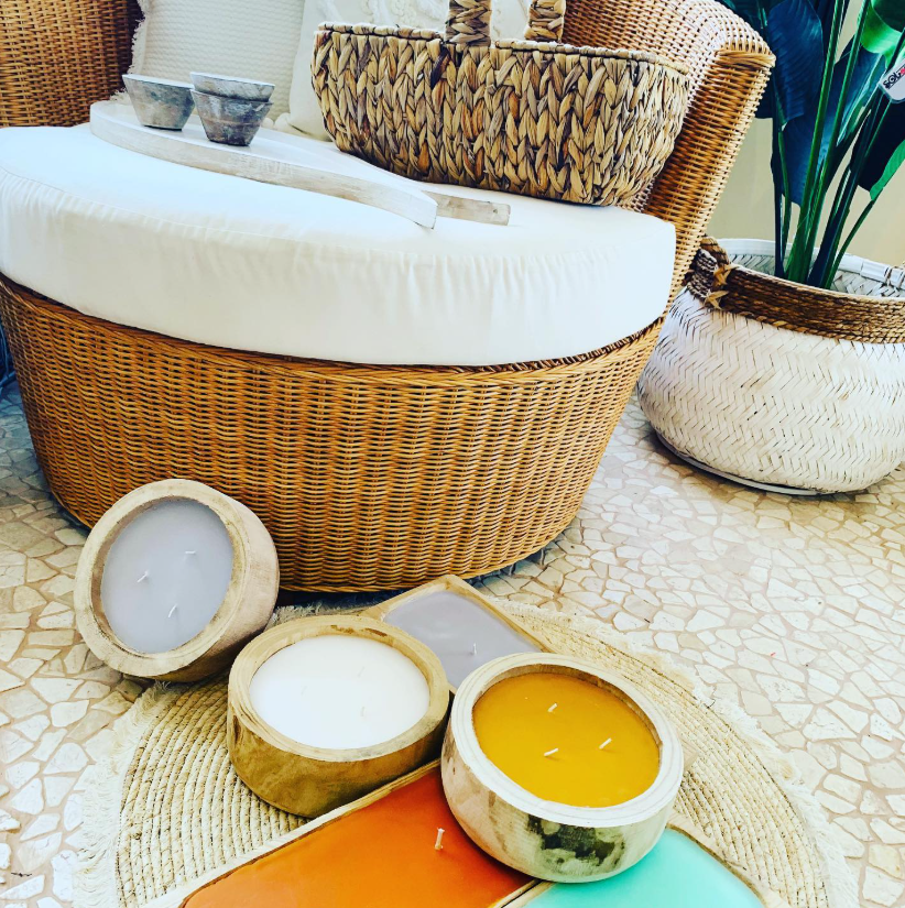 Una silla de mimbre está rodeada de velas y una planta.