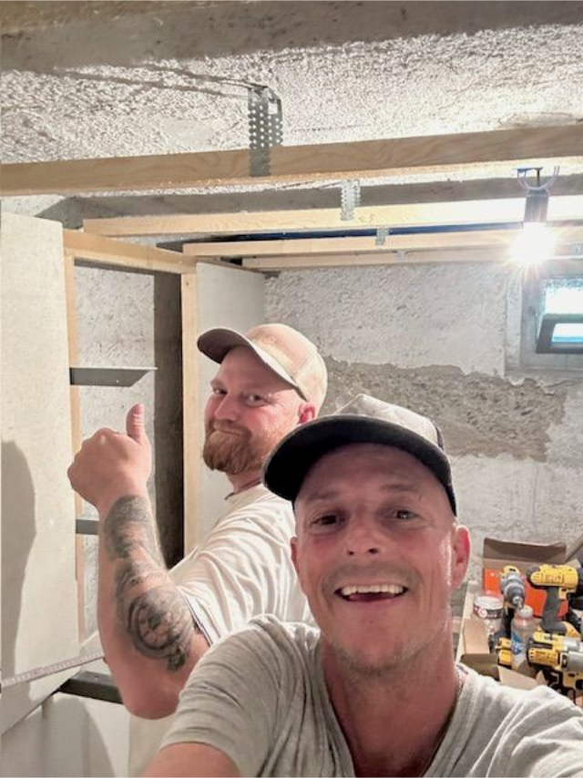 Zwei Männer zeigen in einem Keller den Daumen nach oben. Ein Mann lächelt in die Kamera, der andere lächelt ebenfalls.