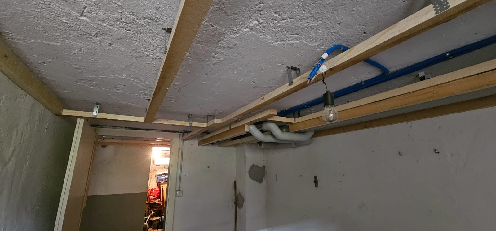 Ein Raum mit einer Decke, die aus Holzbalken und Rohren gebaut wird.