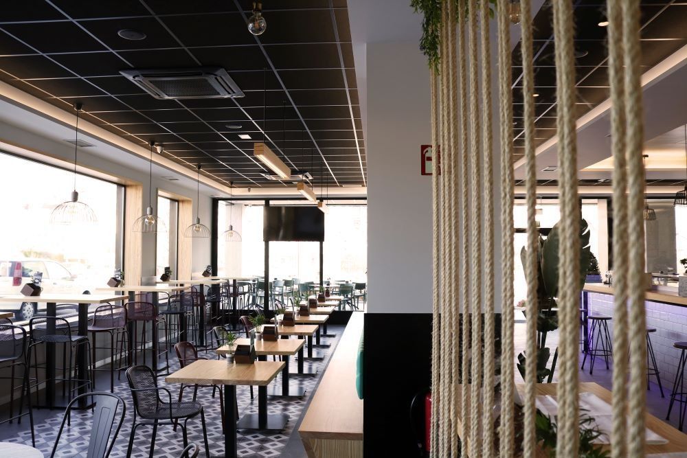 Un restaurante con mesas y sillas y un divisor de cuerda.