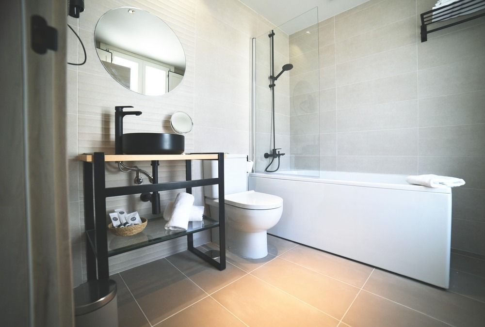 Un baño con inodoro, lavabo, bañera y espejo.