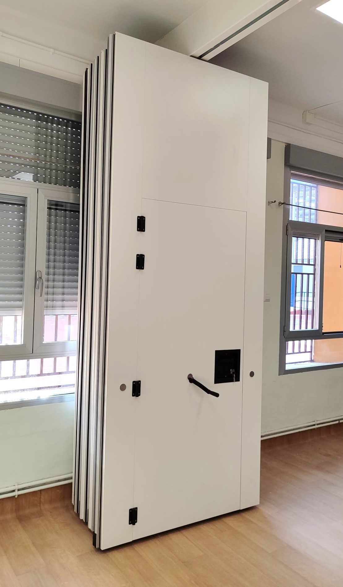 Una gran puerta blanca está en una habitación al lado de una ventana.