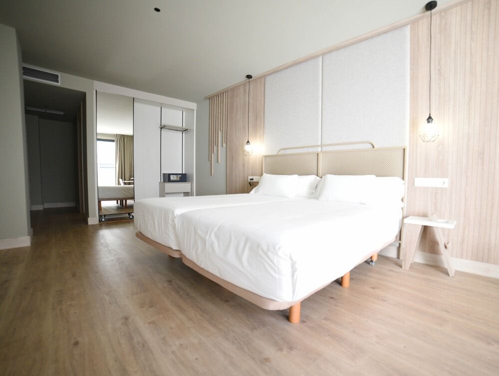 Una habitación de hotel con dos camas y suelo de madera.