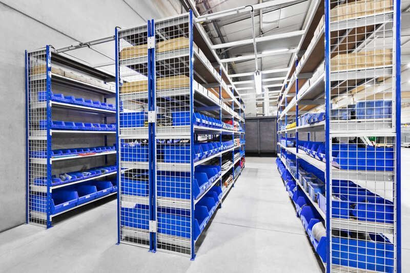 Un almacén lleno de estantes llenos de contenedores y cajas azules.