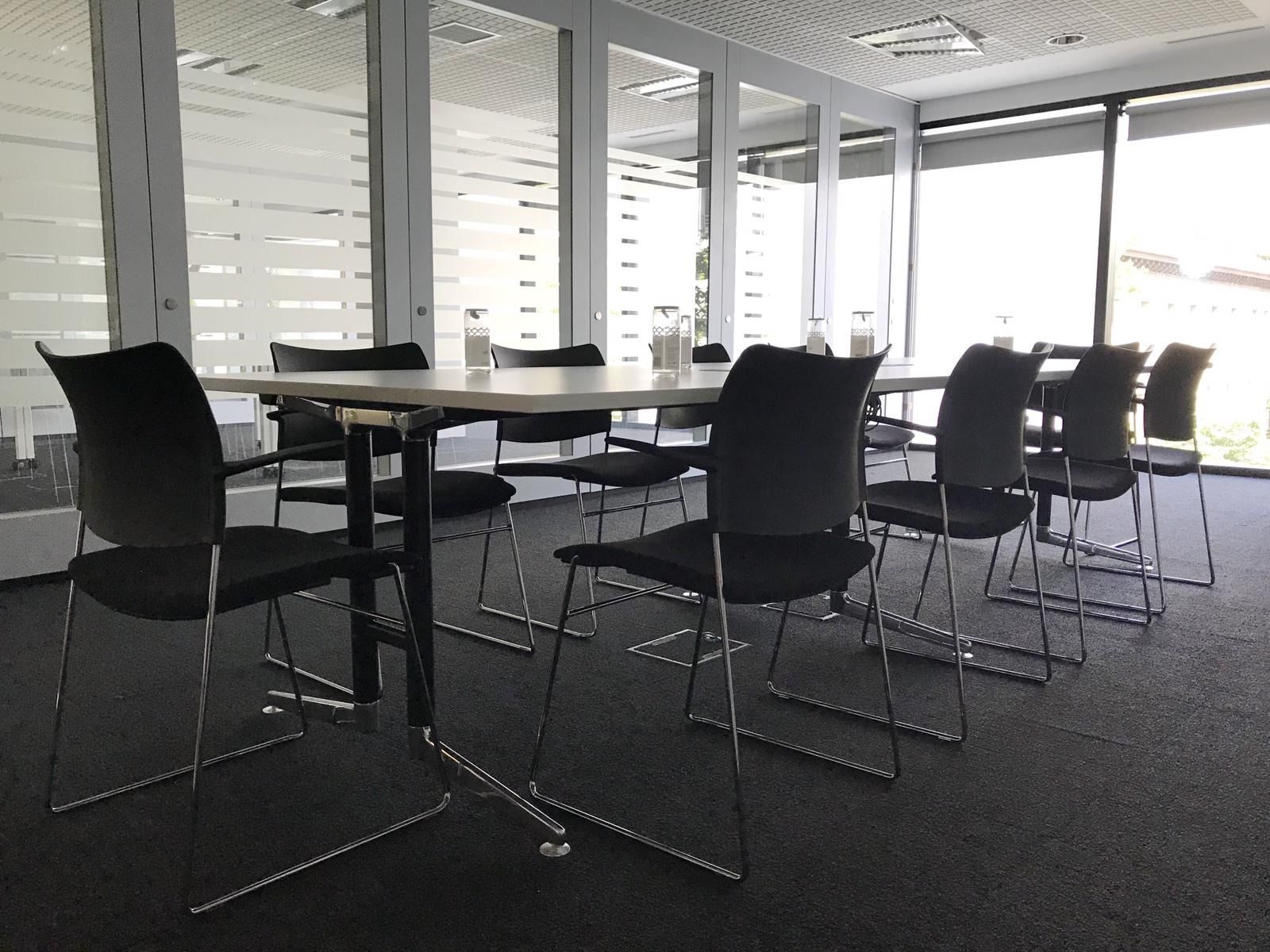 Una sala de conferencias con mesas y sillas y una gran ventana.