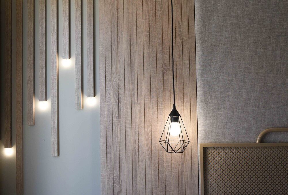 Un dormitorio con una pared de madera y una lámpara colgante que cuelga del techo.