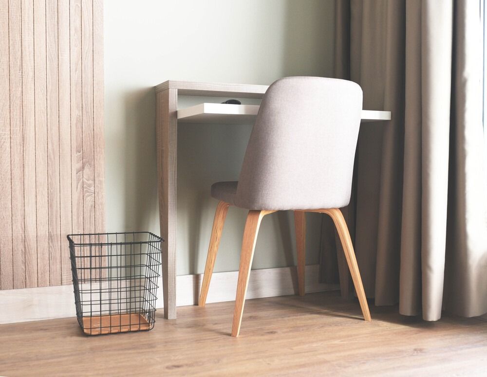 Una silla está sentada en un escritorio en una habitación al lado de una ventana.