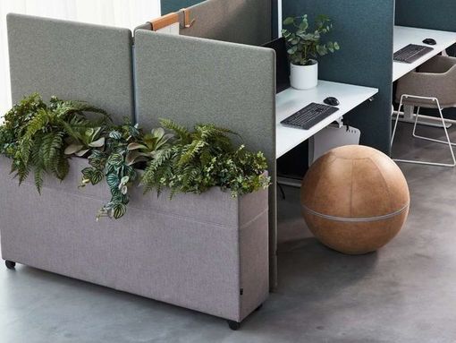Un cubículo con un escritorio, una silla y una jardinera con plantas.