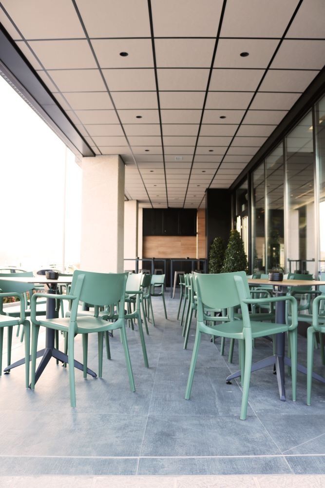Una fila de sillas y mesas verdes en un restaurante.