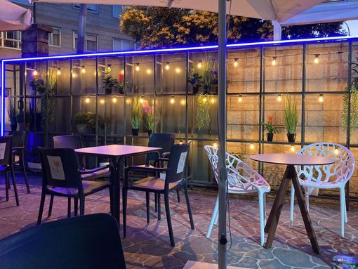 Un patio con mesas y sillas y sombrillas por la noche.