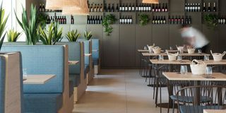 Un restaurante con mesas y cabinas y botellas en la pared.