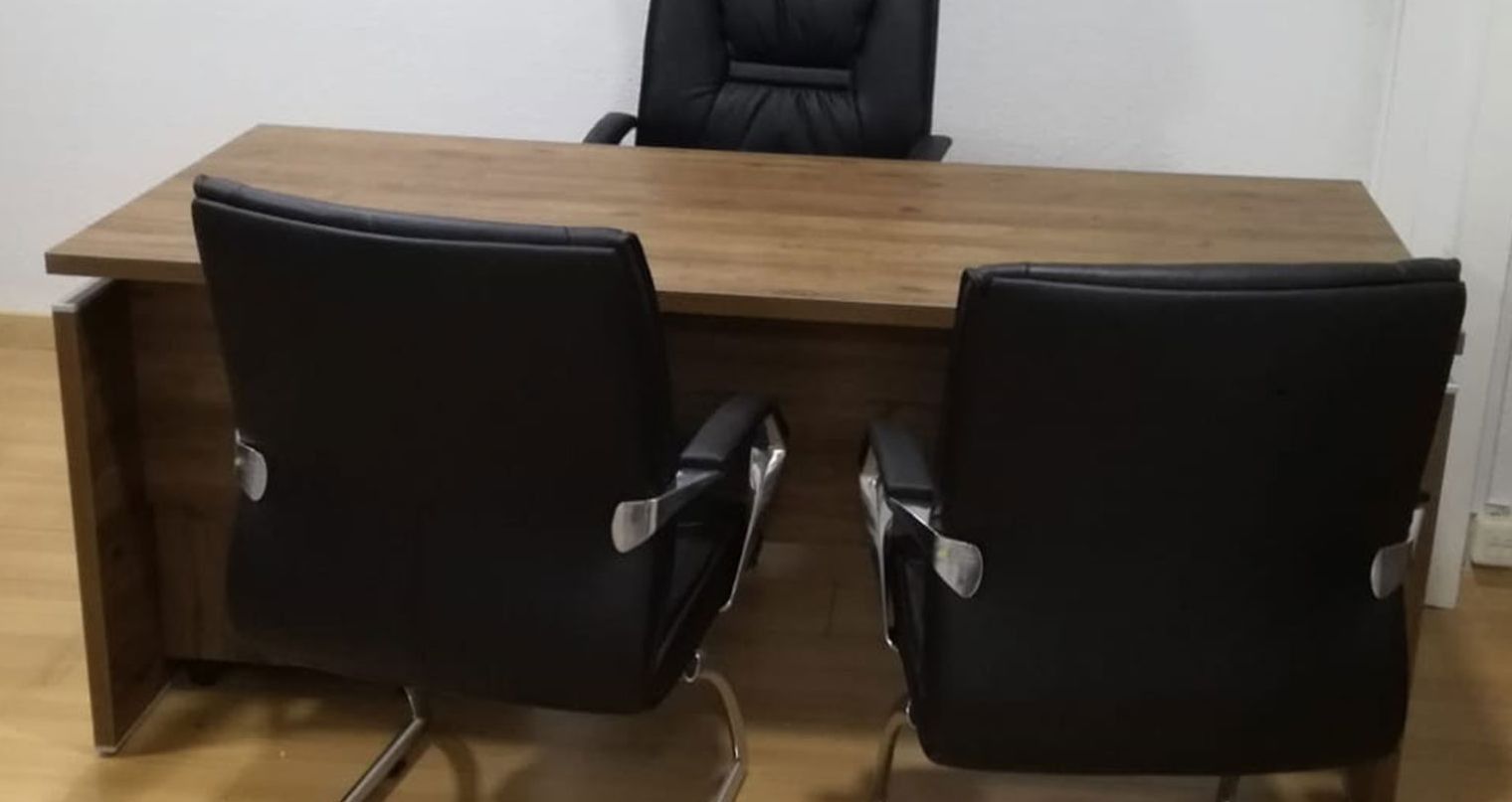 Dos sillas de oficina negras están junto a un escritorio de madera.