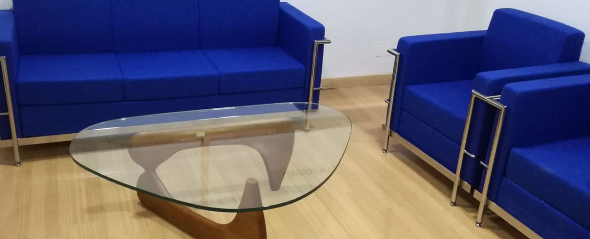 Una sala de estar con muebles azules y una mesa de café de cristal.