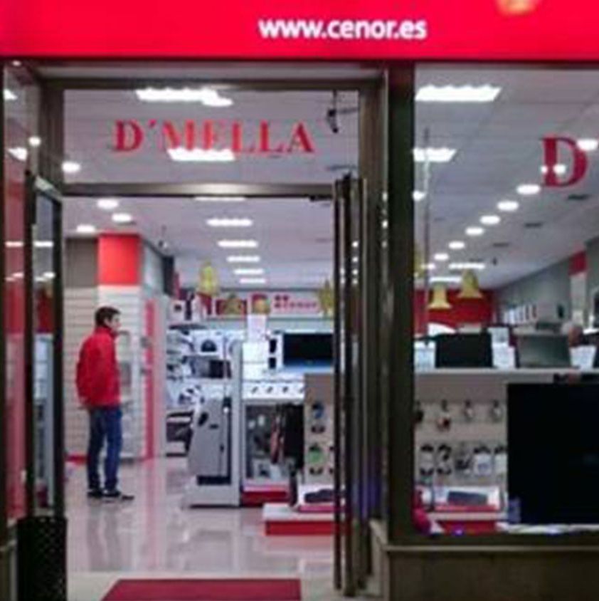 Un hombre con una chaqueta roja está parado en la puerta de una tienda llamada D'Mella.