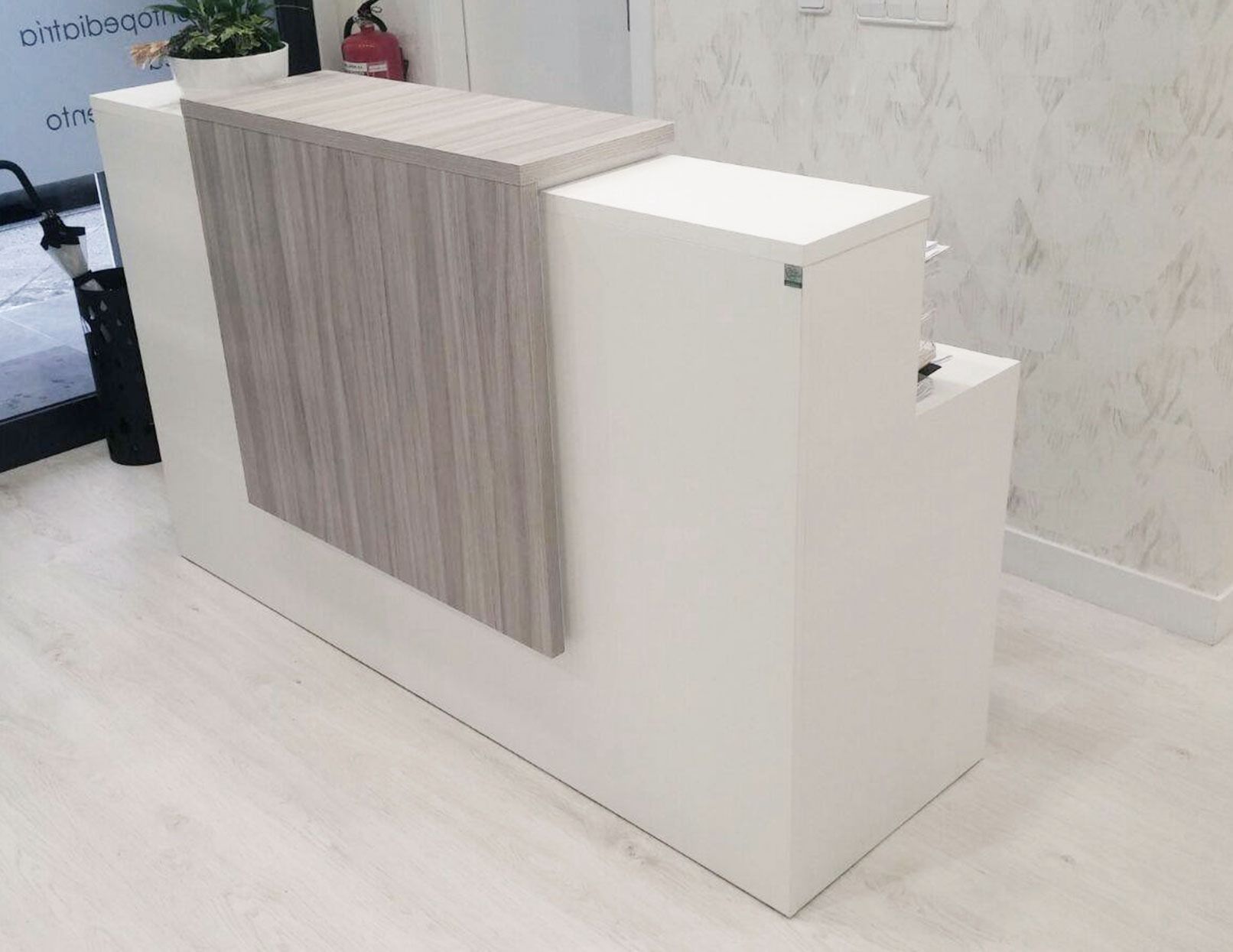Un mostrador de recepción blanco con superficie de madera en una habitación.