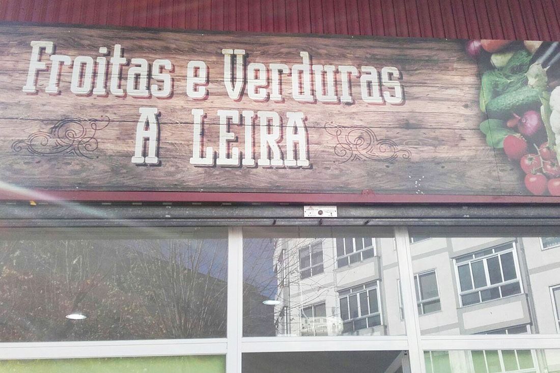 Un escaparate con un cartel que dice frutas y verduras a leira