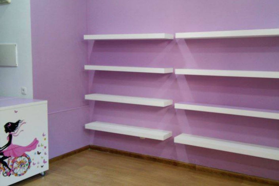 Una habitación con paredes moradas y estantes blancos.