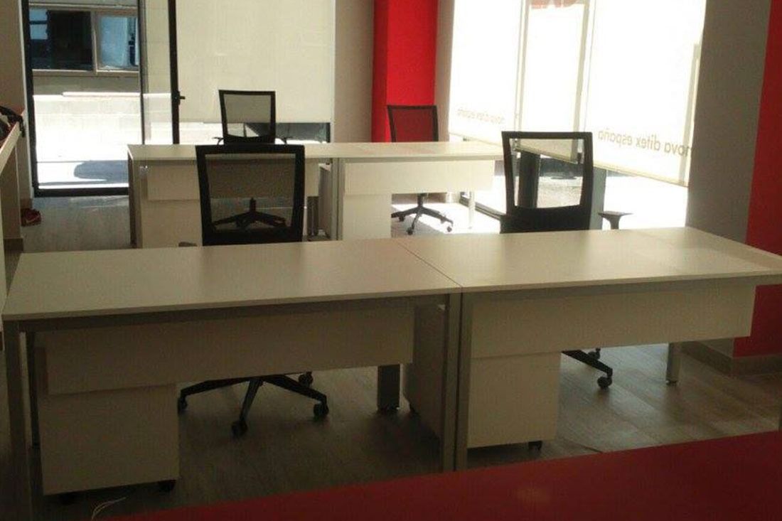 Una fila de escritorios y sillas blancas en una oficina.