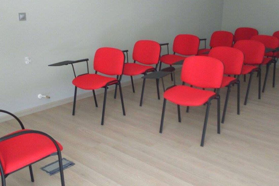 Una fila de sillas rojas están alineadas en una habitación.