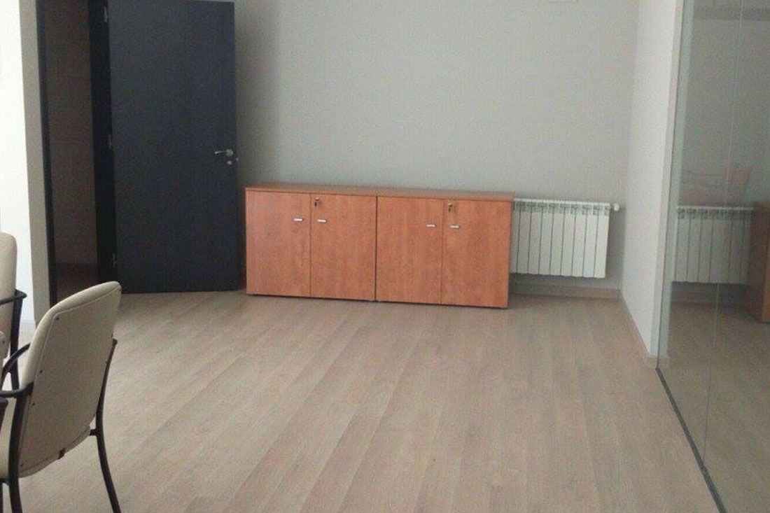 Una habitación con suelo de madera, sillas, una cómoda y un radiador.