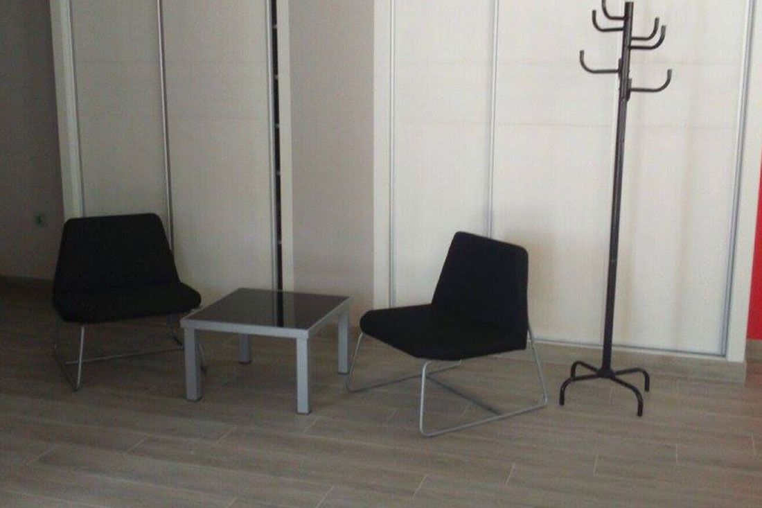 Una habitación con dos sillas, una mesa y un perchero.