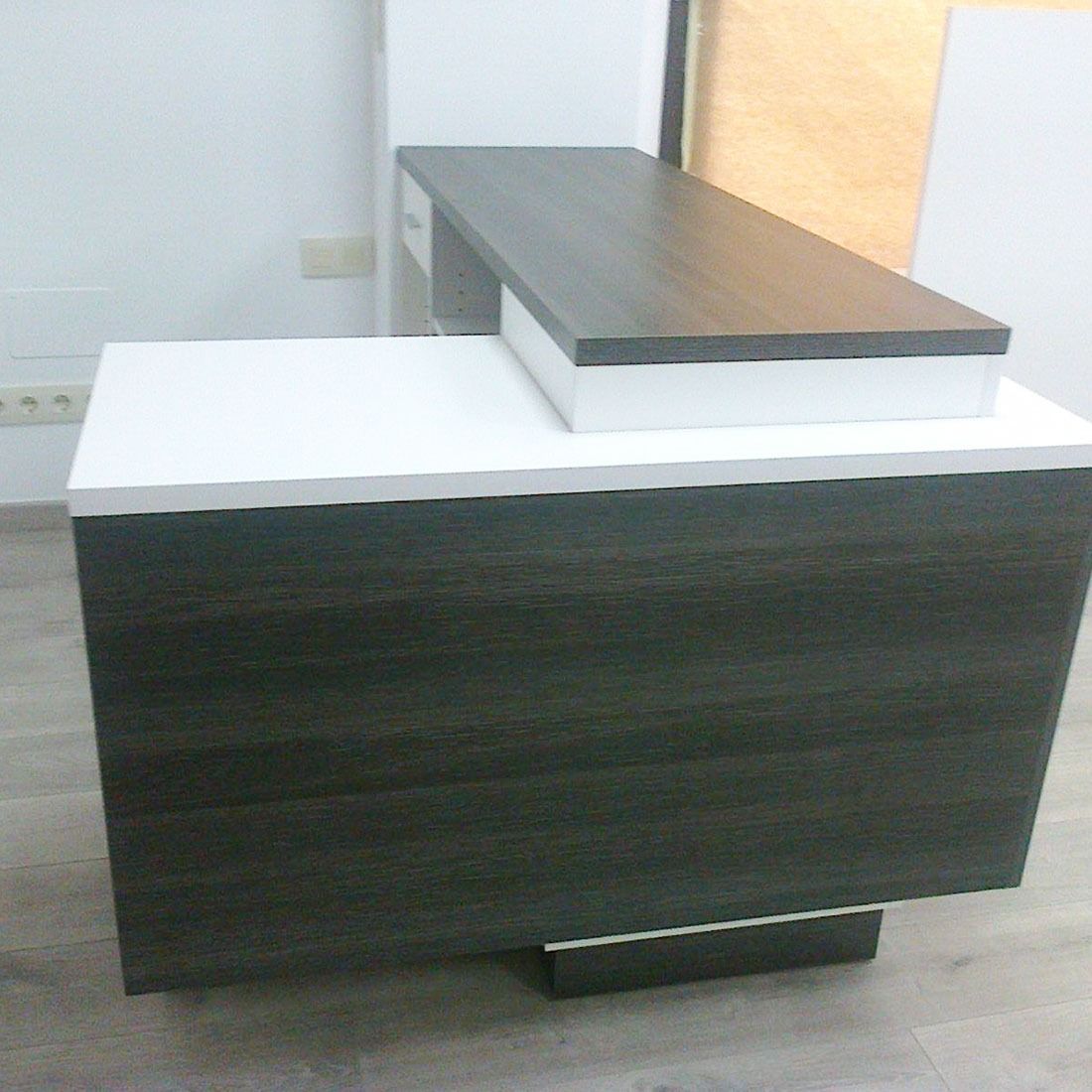 Una mesa de madera con una tapa blanca está colocada sobre un suelo de madera.