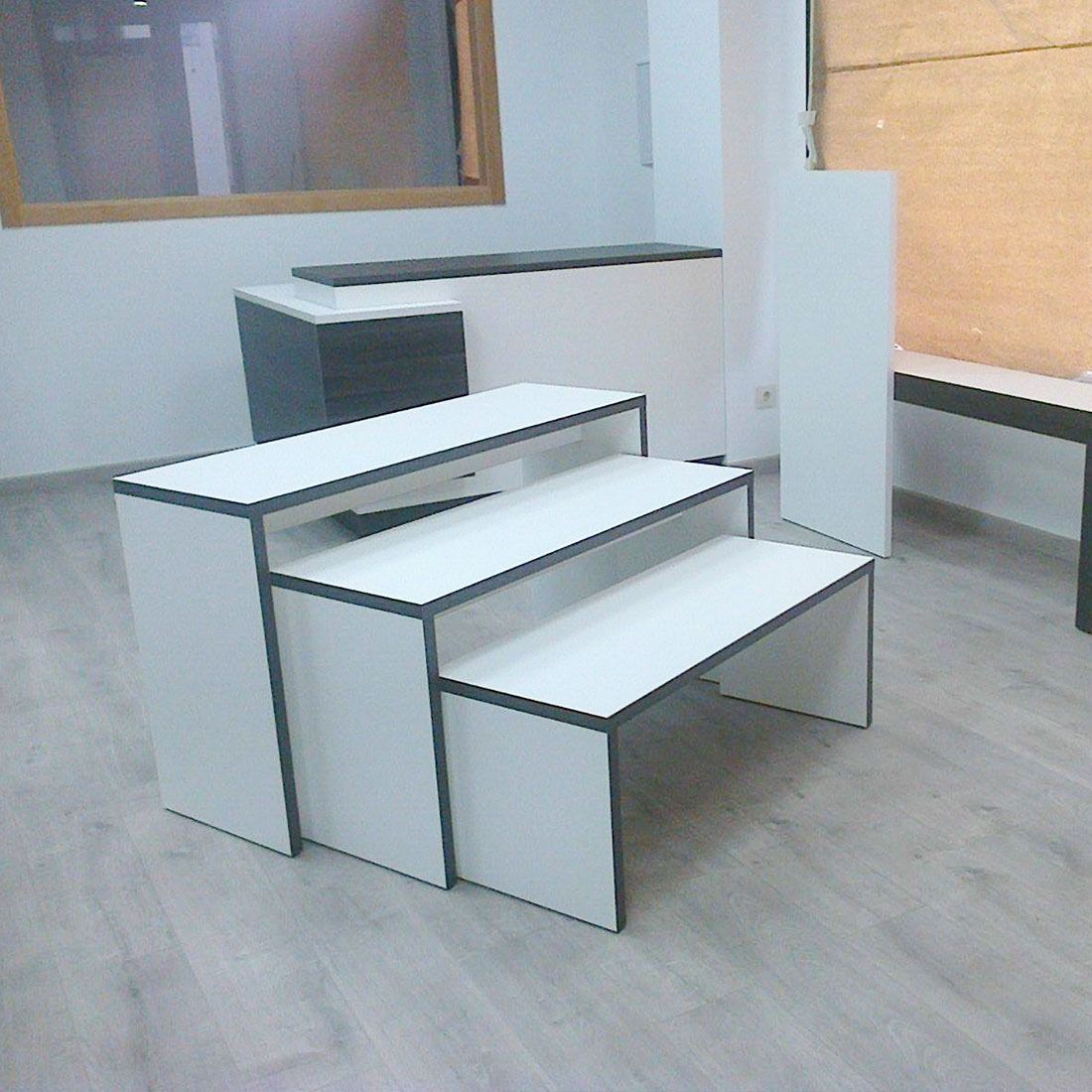 Una habitación con tres mesas blancas y un banco.