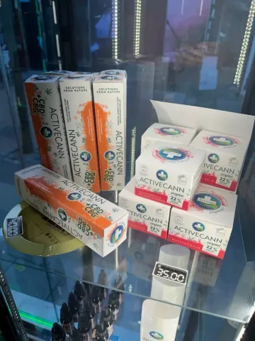 Cajas de productos de CBD en una vitrina. Envase naranja y blanco con logotipo azul.