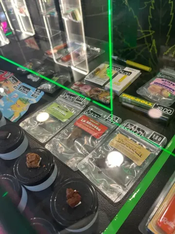 Vitrina con productos de cannabis envasados, incluidos comestibles, en estantes con láser verde.